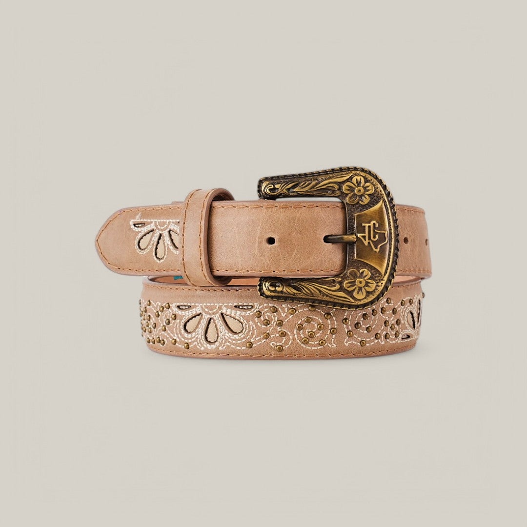 The Sierra Fawn Belt - Texas Buckle features elegant floral carvings on tan leather with a decorative brass buckle, coiled attractively on a beige background, making it an essential women’s wardrobe accessory.