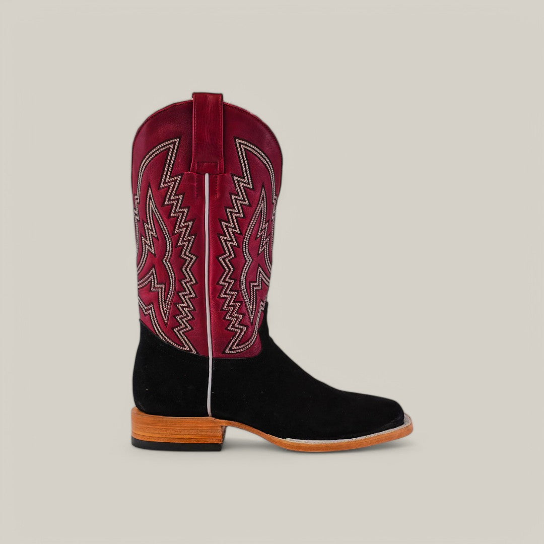 A single Black Suede - Platinum square-toe cowboy boot has a black lower section and burgundy upper shaft with intricate pink and white stitching, set against a plain gray background. It features a wooden sole and heel.