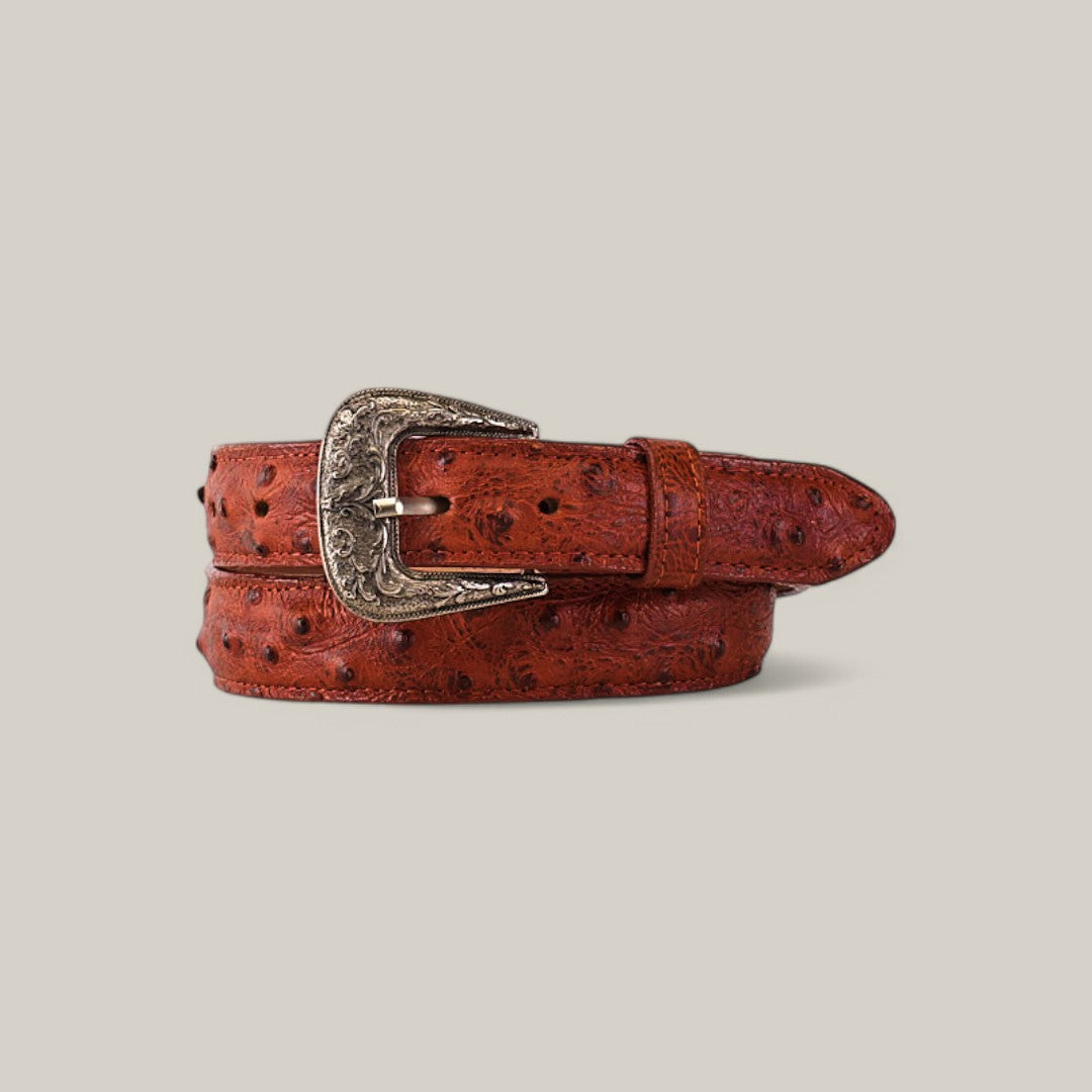 A rolled-up Cognac belt, made with ostrich print and featuring an intricate Texas buckle, set against a plain light gray background.