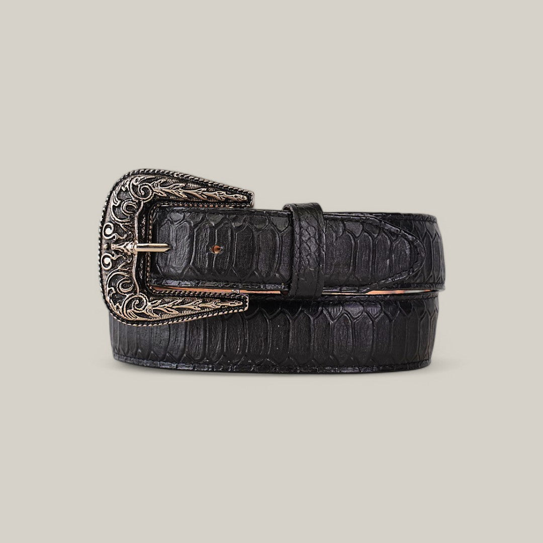 The Python Print Black Belt - Texas Buckle showcases a textured, crocodile-like pattern in black leather, paired with an ornate silver buckle featuring intricate engravings, all set against a plain beige background.