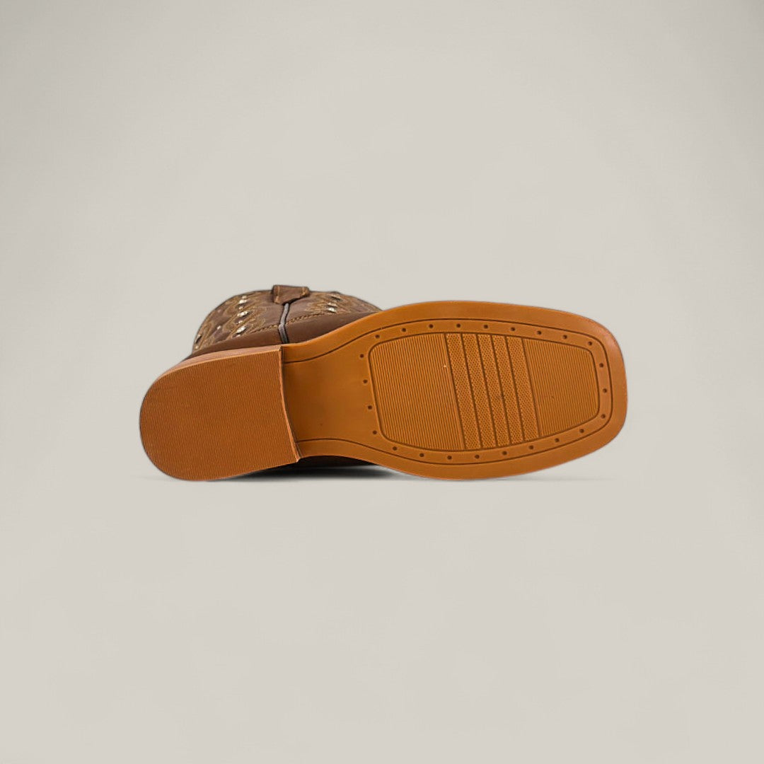The Premiere Texas Copper - Square Toe Kids Boots are shown on their side, highlighting the treaded rubber sole with rectangular patterns and detailed stitching, embodying true Texas style against a plain beige background.