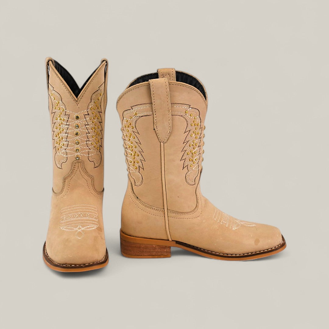 The Orion Suede Bone - Square Toe Kids Boots feature tan premium suede, detailed white and yellow stitching, wooden heels, and pointed toes, showcased against a simple light background.