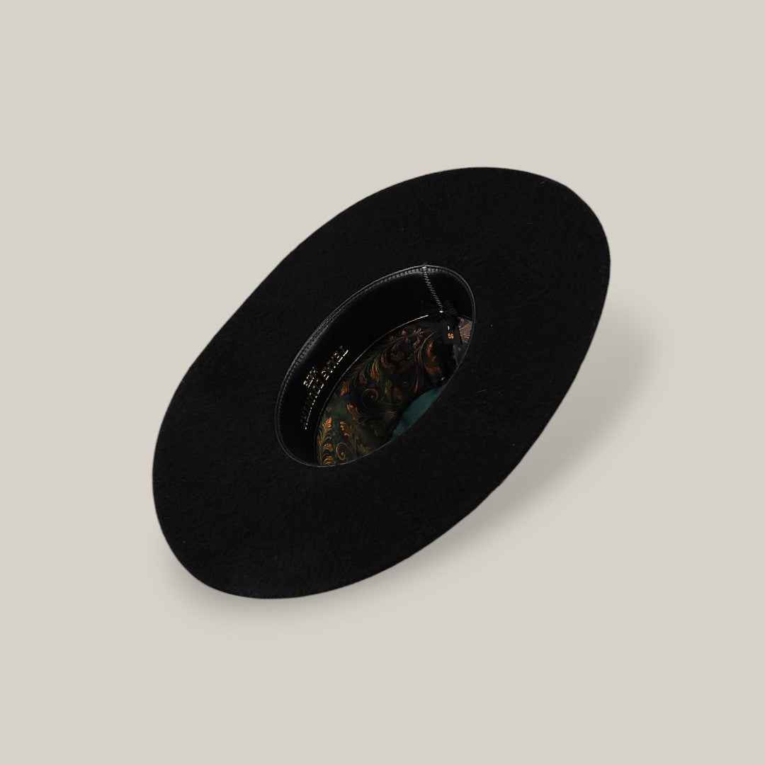 The 25X Grizzly - Black - TC Hat is a wide-brimmed luxury black hat with a decorative patterned inner band, shown from above on a plain beige background.