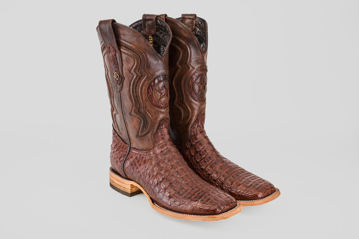 A pair of Exotic Caiman Horn Back - Brown - Square Toe boots, featuring textured details and wooden heels, displayed against a light grey background.