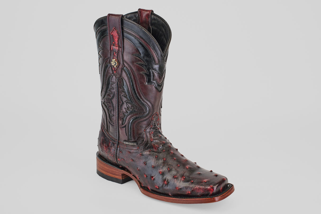 The Exotic Ostrich - Black Cherry - Rodeo Toe features decorative stitching, red accents, and a textured ostrich leather surface, showcased on a light gray background—an eye-catching exotic boot.