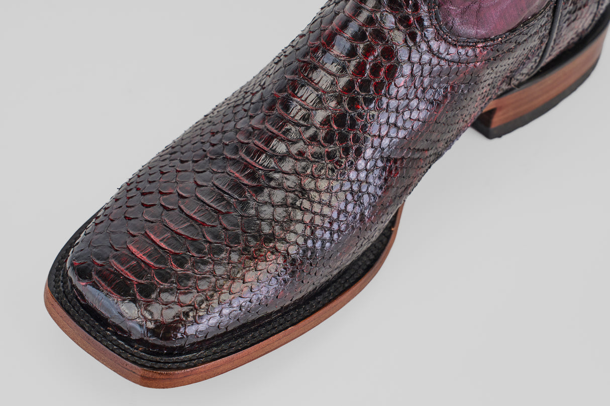 Close-up of the Tanner - Black Cherry - Square Toe cowboy boot with shiny dark red and black snakeskin, square toe, and light brown leather sole against a plain light background.
