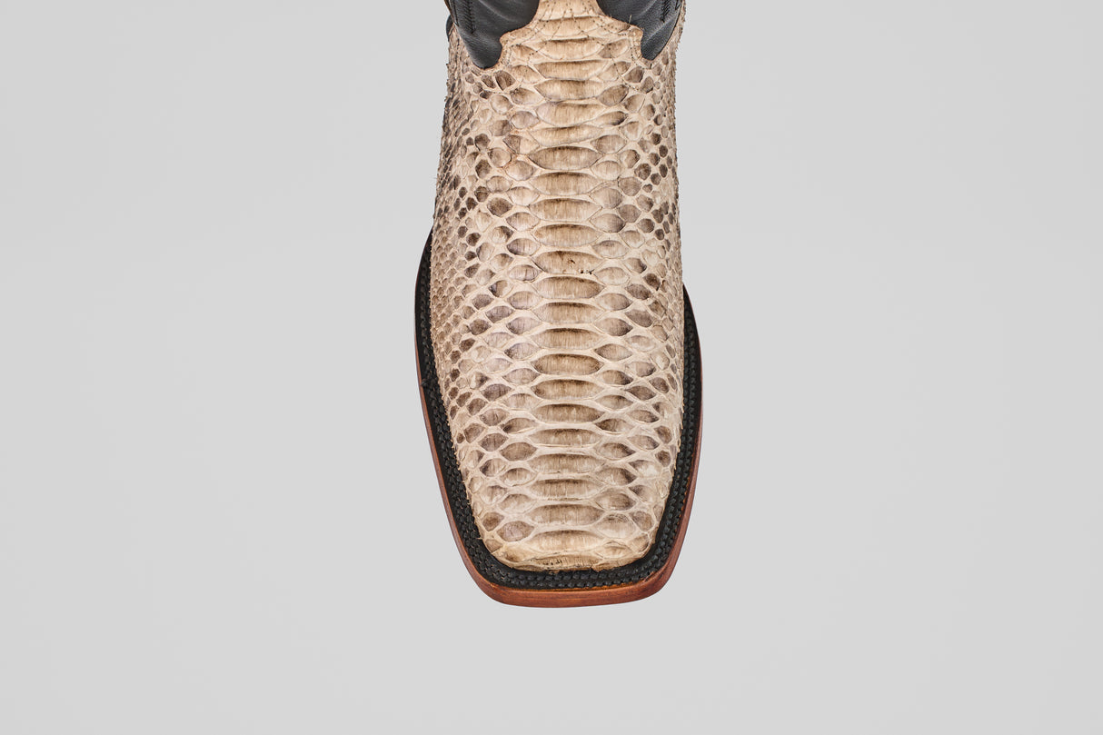 Top view of the Tanner - Natural - Rodeo Toe cowboy boot in tan natural python snakeskin, featuring a square toe, dark brown trim, and wooden sole, set against a plain light gray background.
