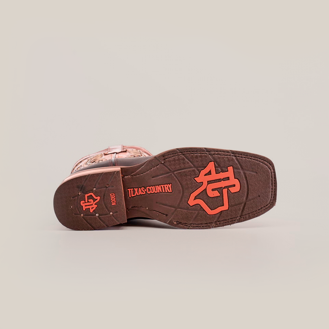 The image displays the sole of an Azkar Moka boot with red text, Texas Country, and a decorative emblem. The slip-resistant design ensures quality grip. The premium brown cowhide cowboy boot is set against a plain white background.