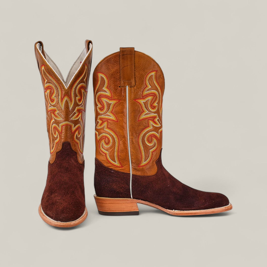 The Dusty - Classic Brown - Roper Toe boots feature brown suede feet, light brown leather shafts, and intricate yellow and red stitching, displayed against a plain beige background.
