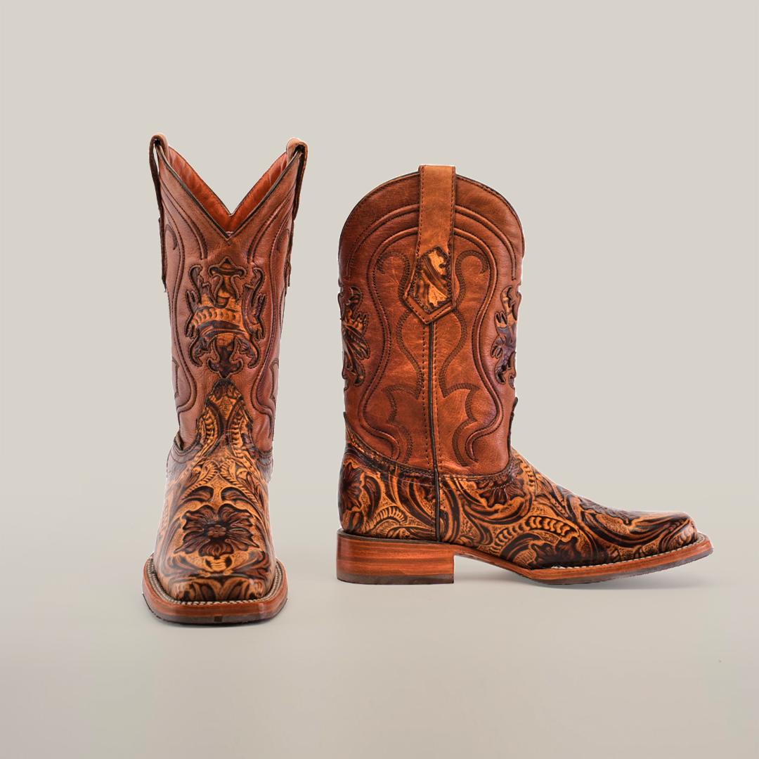 A pair of Handtooled Leave Orix cowboy boots with detailed engravings, made from premium cowhide leather. The left boot stands upright while the right reveals its slip-resistant sole on a plain white background.