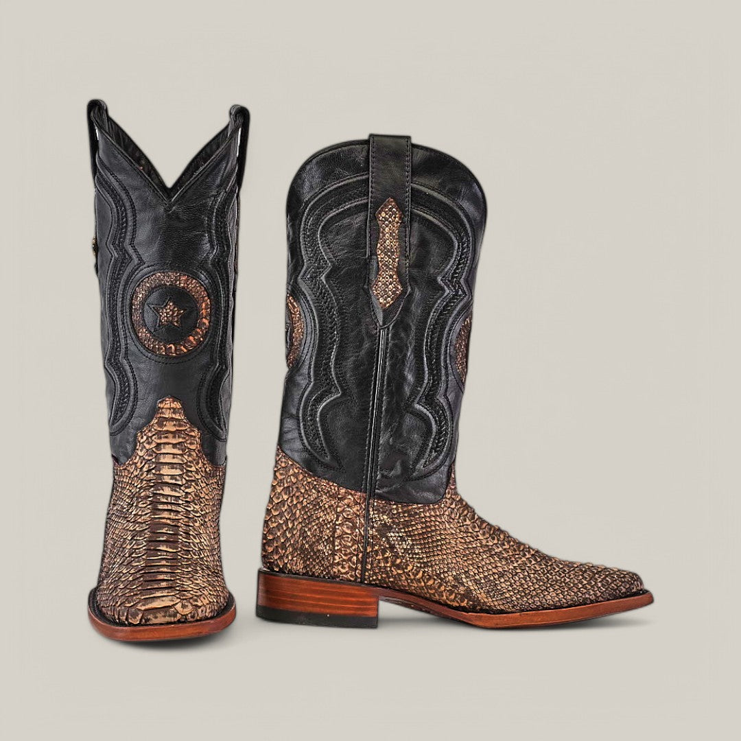 The Exotic Python - Rustic Bone cowboy boots, crafted from black leather and rustic brown python, highlight a Western charm with intricate stitching and textured patterns. A square toe and wooden heel complete the look as one boot faces forward, the other to the side against a plain backdrop.