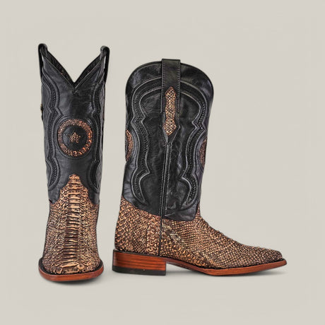 The Exotic Python - Rustic Bone cowboy boots, crafted from black leather and rustic brown python, highlight a Western charm with intricate stitching and textured patterns. A square toe and wooden heel complete the look as one boot faces forward, the other to the side against a plain backdrop.