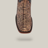 Close-up of the Exotic Python - Rustic Bone boot crafted from python leather, showcasing a textured brown pattern. Featuring a square toe and black trim, it perfectly captures Western appeal against a simple gray background.