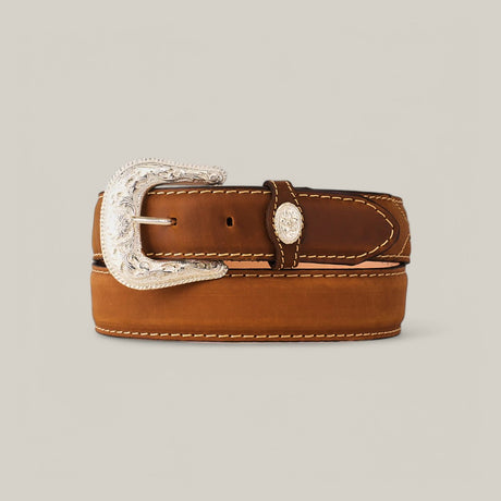 The Honey Plain Belt - Silver Buckle, a brown leather accessory with white stitching, is neatly rolled. It features an ornate silver buckle with intricate engravings, adding a decorative flair against a plain, neutral background.