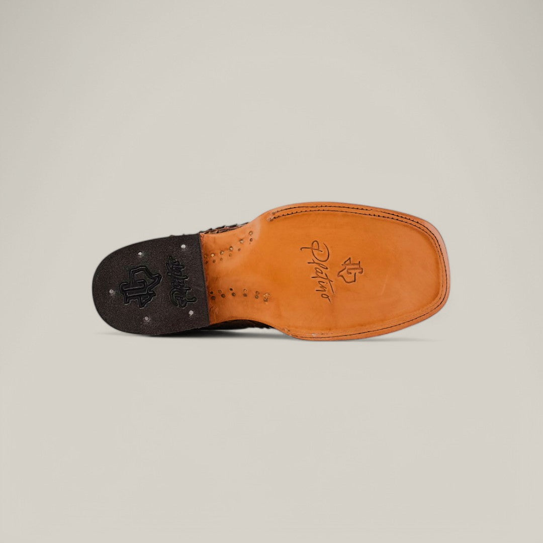 The image shows the underside of an Exotic Python - Tamarindo - Square Toe shoe with a tan leather sole and black heel. It features exotic python leather accents and artistic engravings, including a signature and symbols on the heel and arch, against a neutral background.