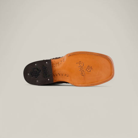 The image shows the underside of an Exotic Python - Tamarindo - Square Toe shoe with a tan leather sole and black heel. It features exotic python leather accents and artistic engravings, including a signature and symbols on the heel and arch, against a neutral background.