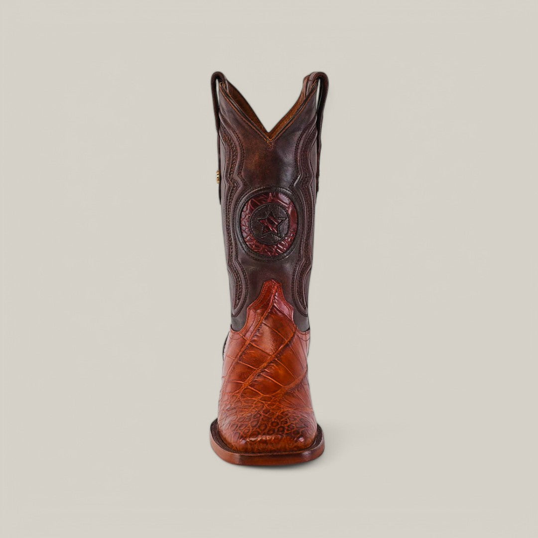 A cowboy boot with intricate stitching and a star on the shaft in Cognac Alligator Hornback leather, featuring a square toe design and textured patterns, is set against a plain beige background. Called Exotic American Alligator Hornback - Cogñac - Square Toe.