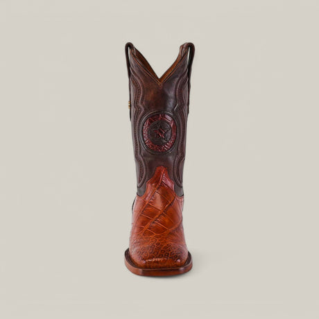 A cowboy boot with intricate stitching and a star on the shaft in Cognac Alligator Hornback leather, featuring a square toe design and textured patterns, is set against a plain beige background. Called Exotic American Alligator Hornback - Cogñac - Square Toe.