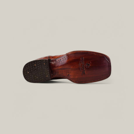 Bottom view of the Exotic American Alligator Hornback - Cogñac shoe on a light gray background, highlighting the textured sole and stitching. The embossed logo and text on the square toe sole evoke an exotic boots charm.