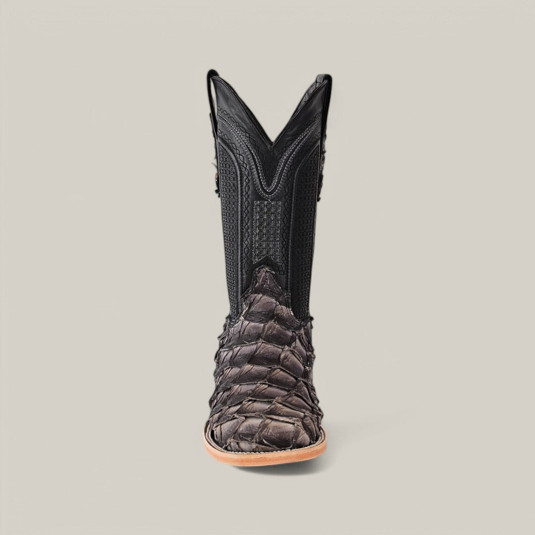 A single Exotic Pirarucu Fish boot with a square toe, made from dark, textured skin and smooth black leather with decorative stitching, rests on a light gray background, highlighting the stylish use of sustainable materials.