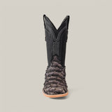 A single Exotic Pirarucu Fish boot with a square toe, made from dark, textured skin and smooth black leather with decorative stitching, rests on a light gray background, highlighting the stylish use of sustainable materials.