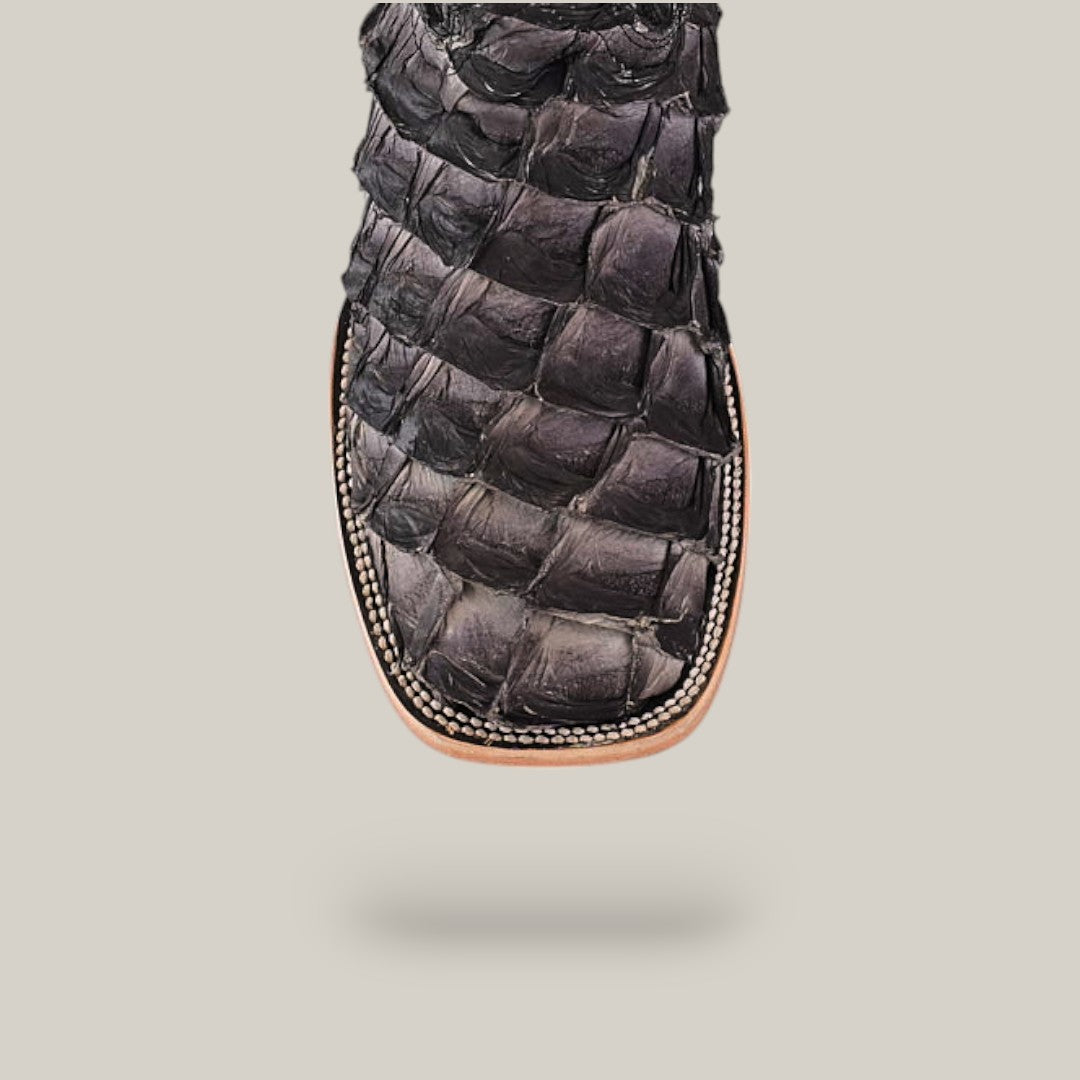 Close-up of the Exotic Pirarucu Fish - Gray - Square Toe boot features textured leather and detailed edge stitching, set against a light gray background, emphasizing its sustainable materials.