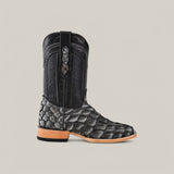 Set against a neutral backdrop, the Exotic Pirarucu Fish - Newspaper - Square Toe boot flaunts black textured exotic leather with intricate stitching, a decorative pull strap, and a modern square toe, complemented by a natural-colored sole.