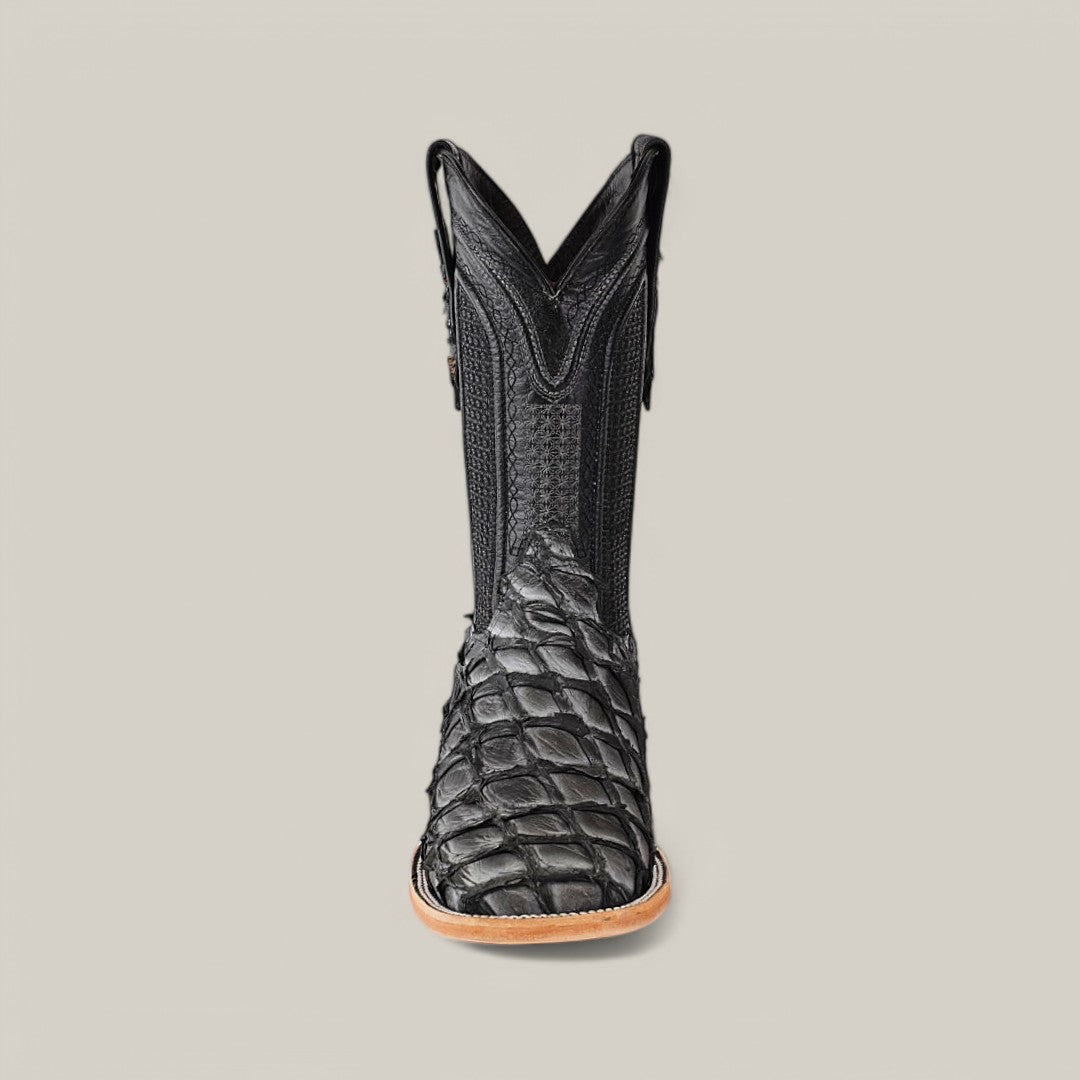 A single Exotic Pirarucu Fish boot, known as Newspaper, crafted from textured leather with a reptile-like pattern, stands upright on a light gray background. It features decorative shaft stitching and a unique square toe, merging traditional style with modern flair.