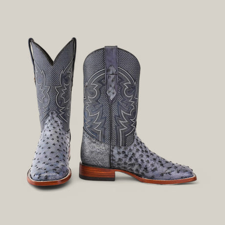 A pair of Exotic Full Quilt Ostrich boots in Safari Gray with intricate patterns and dark gray textures stands against a plain background, featuring square toes and wooden soles. One boot is upright while the other is angled side-on.