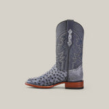 The Exotic Full Quilt Ostrich - Safari Gray - Square Toe boot showcases a textured pattern in a rich gray shade with decorative stitching, paired with a brown wooden heel, all set against a plain light backdrop.