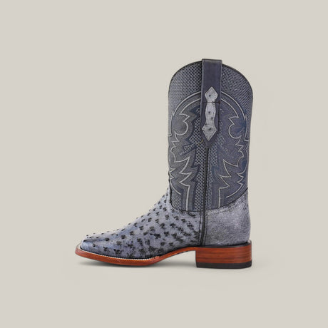 The Exotic Full Quilt Ostrich - Safari Gray - Square Toe boot showcases a textured pattern in a rich gray shade with decorative stitching, paired with a brown wooden heel, all set against a plain light backdrop.