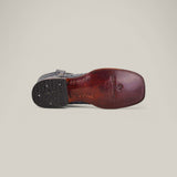 Bottom view of the Exotic Full Quilt Ostrich - Safari Gray - Square Toe boot with a red-brown leather sole featuring engraved text and logo. The black heel has a decorative rubber grip pad, offering sophistication to any ensemble against the plain light gray background.