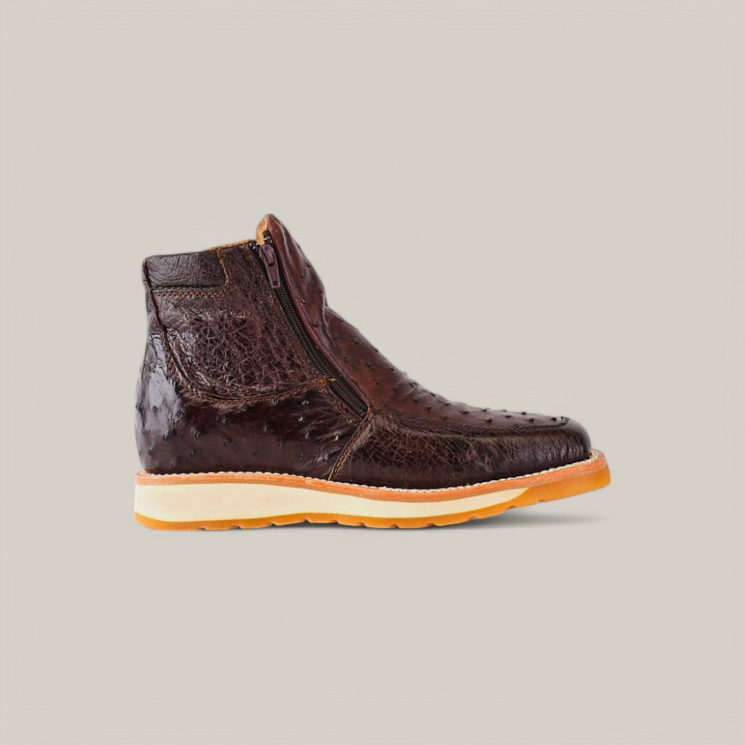 The Exotic Ostrich Dark Brown Ankle Boot boasts a textured look with a side zipper and a light tan rubber sole, elegantly displayed against a plain light gray background.