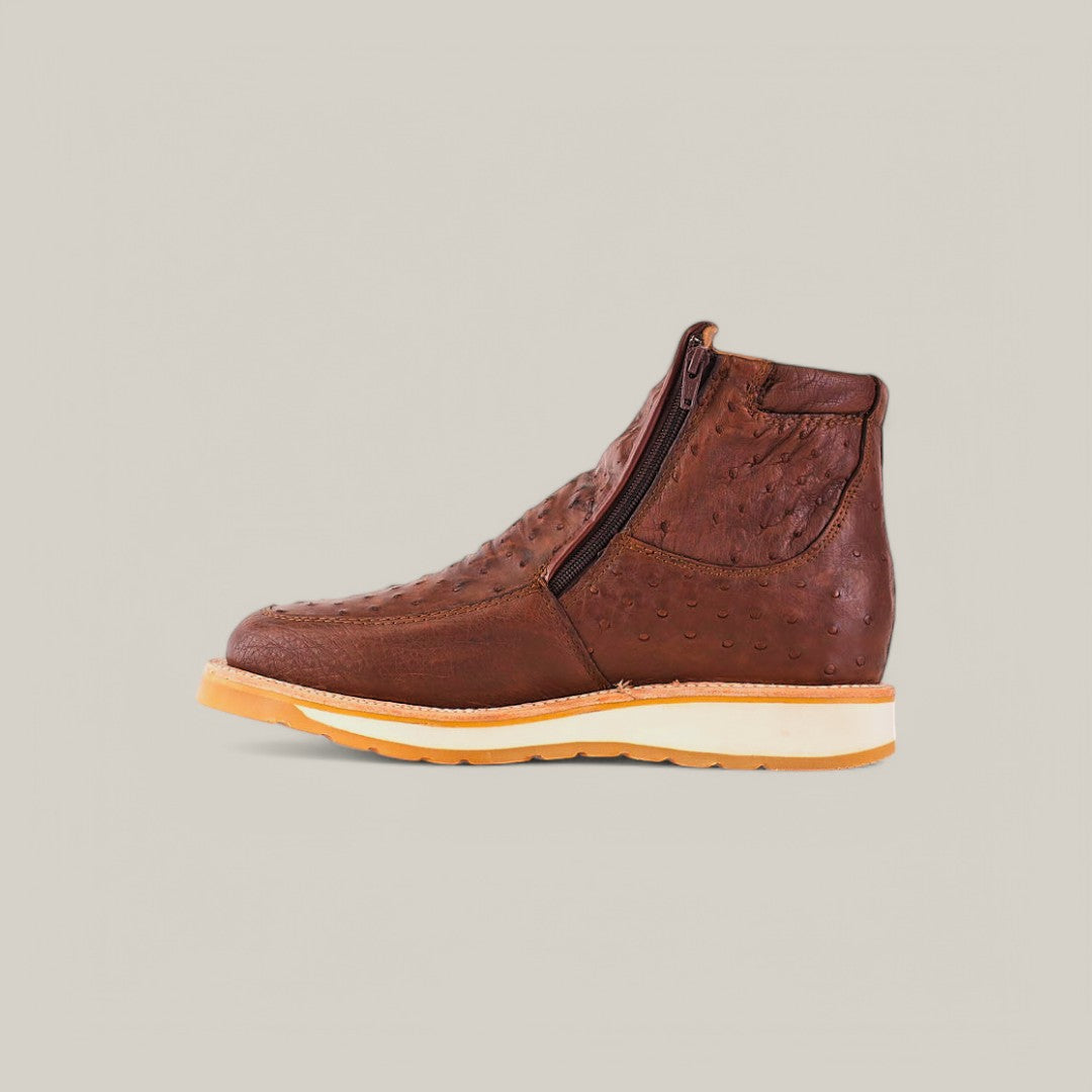 The Exotic Ostrich - Mink - Ankle Boot boasts a textured brown surface and convenient side zipper, set against a beige backdrop. Crafted from rich ostrich leather, it features a luxury tan sole with robust tread.