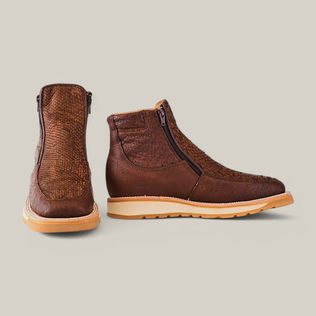 Two Exotic Python Brown Ankle Boots with textured patterns and side zippers sit on a light gray backdrop, showing tan soles; one boot faces side, the other, back.