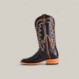 The Exotic Full Quilt Ostrich - Black - Square Toe boot features black ostrich leather, orange and gray stitching, a wooden sole, and embossed texture, showcased against a plain light gray background.