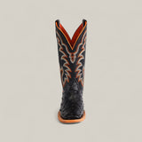 A single Exotic Full Quilt Ostrich - Black - Square Toe boot from the Platinum collection, featuring orange and white stitching and a tan sole, stands upright against a plain light background.