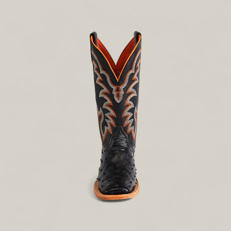 A single Exotic Full Quilt Ostrich - Black - Square Toe boot from the Platinum collection, featuring orange and white stitching and a tan sole, stands upright against a plain light background.