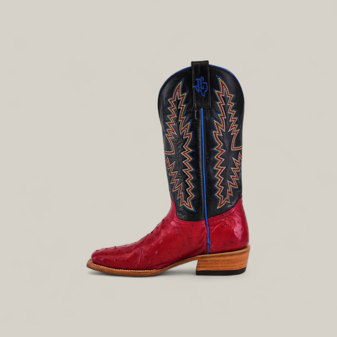 The Exotic Full Quilt Ostrich - Red - Square Toe boot features a red, textured lower half, wooden sole, black upper shaft with colorful zigzag embroidery, blue piping, and a distinctive square toe.