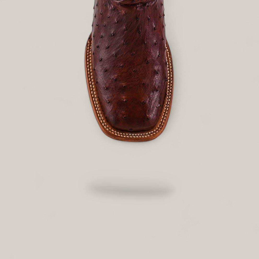 Close-up of the Exotic Full Quilt Ostrich - Red / Brown - Square Toe boot, highlighted from above to showcase decorative stitching, part of the Platinum Collection, displayed on a light beige background with a subtle shadow.