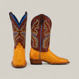 A pair of Exotic Full Quilt Ostrich - Buttercup - Square Toe boots with yellow ostrich leather, brown shafts, detailed yellow and blue stitching, and a blue lining. One boot stands upright; the other is shown in side view.