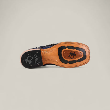 The image displays the sole of the Exotic Pirarucu Fish - Navy Black - Square Toe boot, featuring a tan leather base with black rubber grip details and signature logos near the heel and center, set against a plain light gray background.