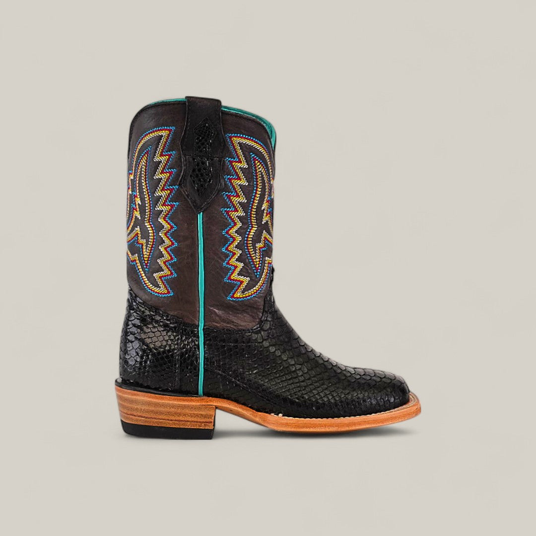 The Exotic Python Black - Square Toe - Kids Boots feature black leather with snakeskin texture, colorful zigzag shaft stitching, a wooden heel, and light brown sole, shown in profile against a beige background.