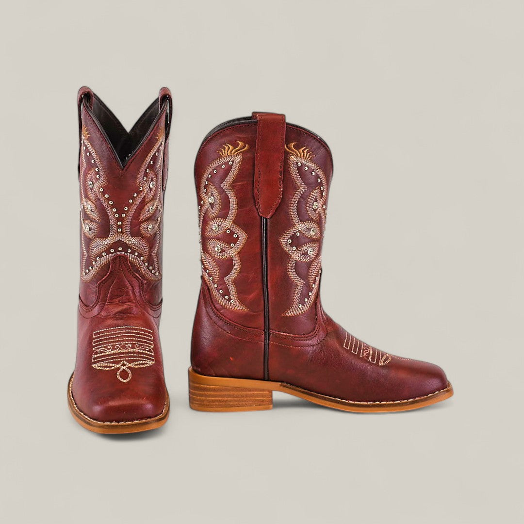 Blake Cognac - Square Toe Kids Boots in red-brown with tan stitching, decorative embroidery, wooden sole, and square toe, featuring intricate shaft and toe patterns—displayed against a plain light background.