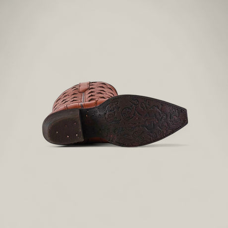 The Marjorie Star Brown - Tall Shaft - Snip Toe boot is shown on its side, highlighting its woven brown leather and a dark brown sole embossed with an intricate floral pattern, set against a plain light background.