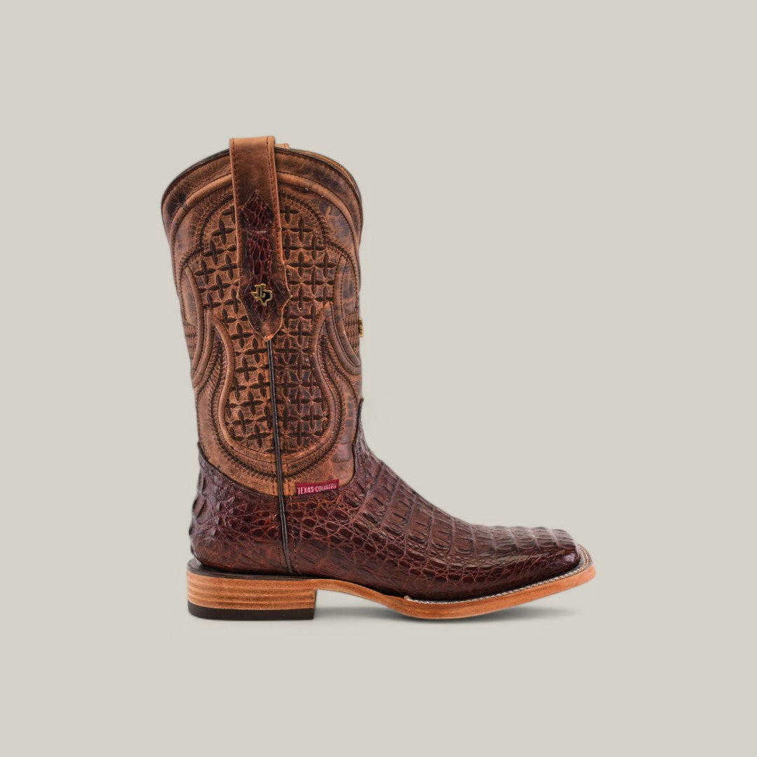 The Exotic Caiman Horn Back - Brown - Square Toe boot is crafted from genuine leather, showcasing intricate stitching and a textured pattern. It features a square toe, stacked wooden heel, and pull strap, standing upright against a plain, light gray background.
