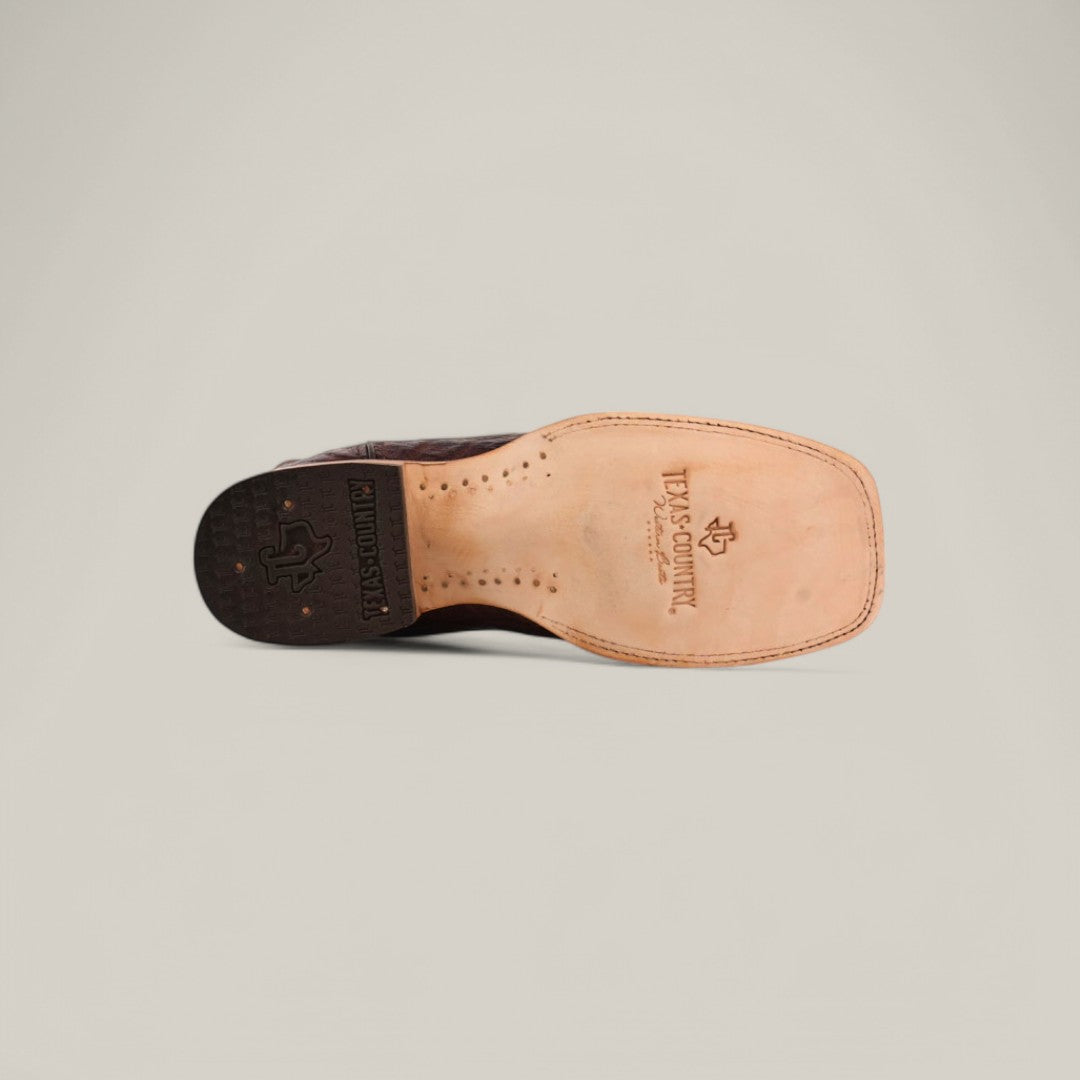 The image displays the sole of the Exotic Caiman Horn Back - Brown - Square Toe boot on a plain background, featuring a square toe and intricate stitching. Logos and branding emphasize the exquisite craftsmanship of these genuine leather cowboy boots.