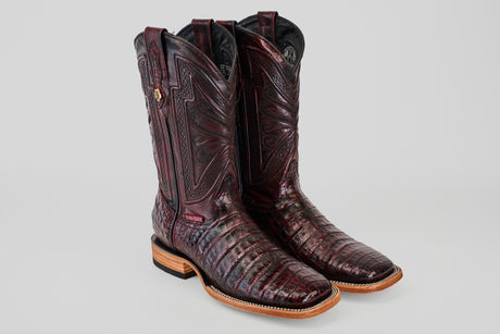 A pair of Exotic Caiman Belly boots in Black Cherry with a square toe, featuring intricate patterns, glossy finish, wooden soles, and black inner lining, displayed on a plain light gray background.