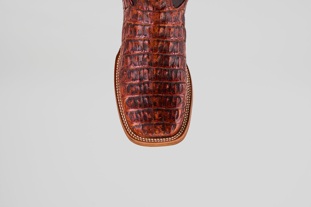 Close-up of the toe of the Exotic Caiman Horn Back - Smoke Cogñac- Square Toe boot, featuring brown, crocodile-patterned caiman leather and decorative edge stitching, set against a light gray background.