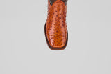 A detailed close-up of the toe of the Austin - Brandy - Square Toe cowboy boot shows its rich, bumpy brown leather texture and square tip, set against a plain light gray background.